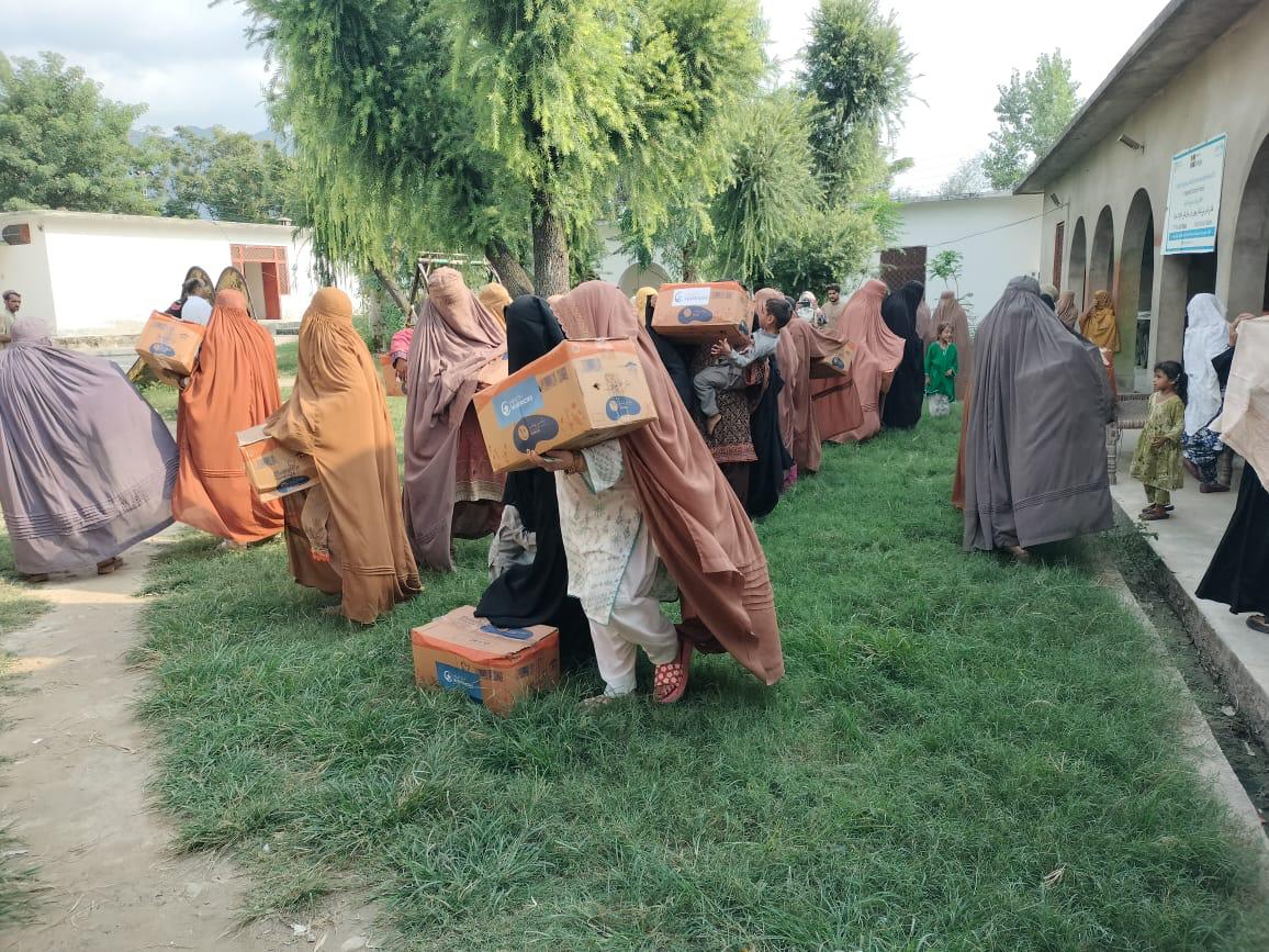Women carrying Health Warriors hygiene supply cartons after distribution in Buner